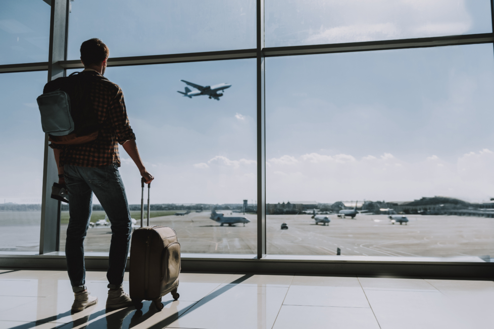 Mann mit Koffer am Flughafen. Anschluss verpasst am Flughafen
