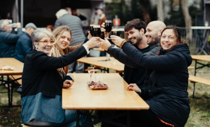 Menschen am Tisch sehen glücklich aus mit Getränk in der Hand.
